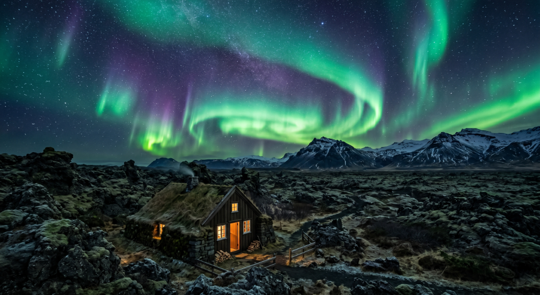 Northern lights aurora borealis dancing over cozy turf house in Iceland's rugged lava field landscape with snow-capped mountains